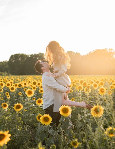 Un homme porte une femme dans un champ de tournesols au coucher du soleil