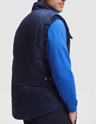 Imagen de un hombre que lleva una sudadera azul royal y un chaleco aolchado en color marino.