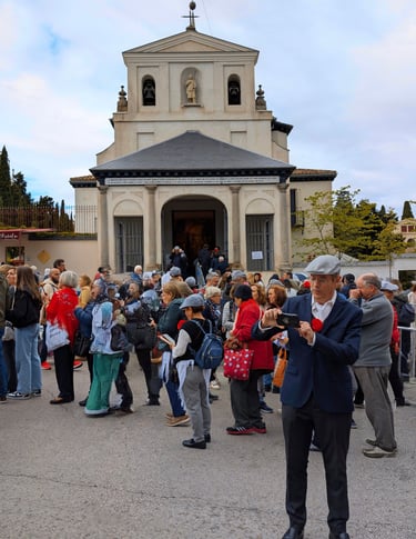 A bustling scene in front of the ermita de San Isidro, with a large crowd of people waiting outside.
