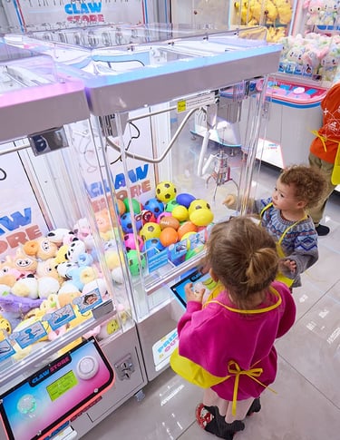 young kids playing a claw machine