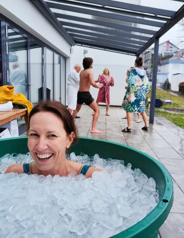 Eine Frau sitzt lachend und fröhlich in einem Eisbad gefüllt mit Eiswürfeln