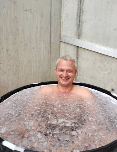 Mann der lachend und fröhlich im Eisbad sitzt