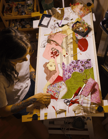 a woman is sitting at a table with a large piece of art work