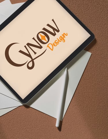 Une tablette graphique avec le logo "Cynow Design" est posée sur une pile de feuilles rigides