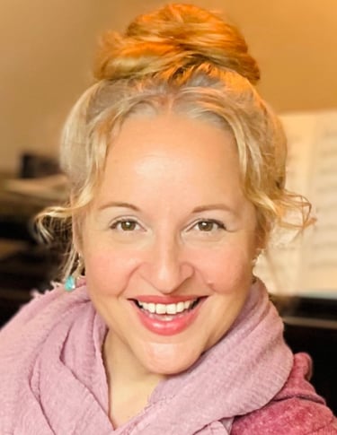 eine Frau - Sina Weidlich - mit Hochgestecken blonden Haaren und einem rosé-farbenen Schal.