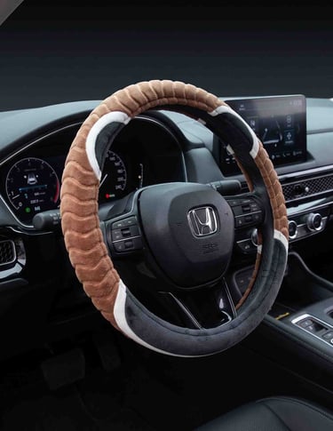 A brown and grey plush steering wheel cover installed on a black Honda dashboard.