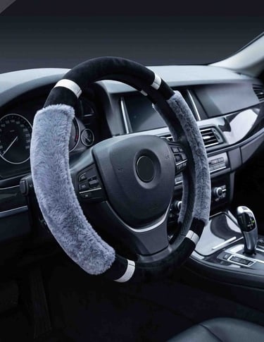 A black and grey faux fur steering wheel cover with sparkling accents inside a luxury car interior.