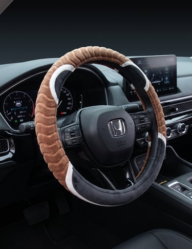 A plush brown and black fuzzy steering wheel cover installed in a modern Honda car interior.
