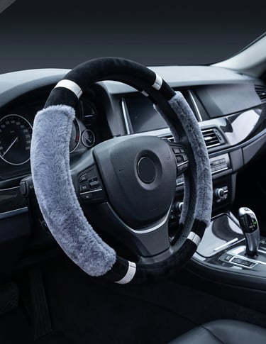 A plush grey and black faux fur steering wheel cover installed on a luxury car dashboard.