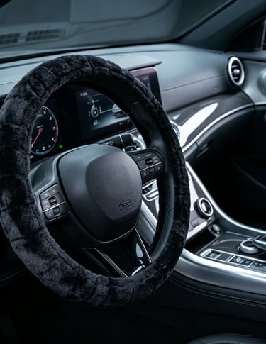 Black fluffy faux fur steering wheel cover installed on a modern luxury car dashboard.