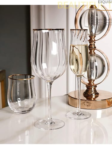 Set of clear wine glasses with elegant gold rims on a styled dining table.