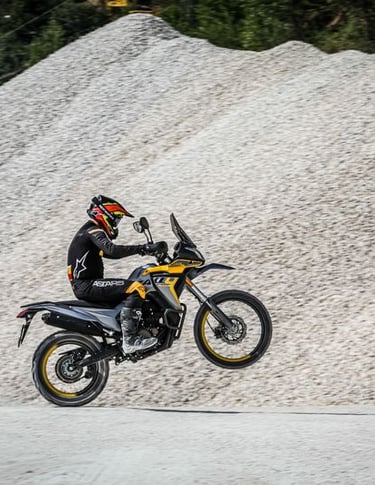 asmuo, važiuojantis motociklu žvyrkeliu