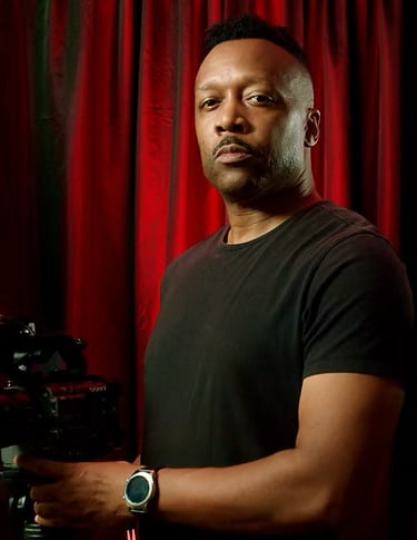 Producer, cinematographer, editor, Pryde Pierce in black shirt, red curtain background,