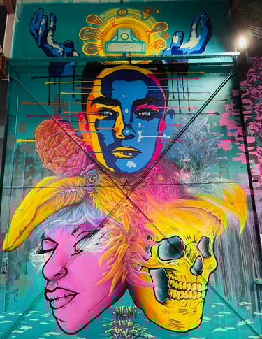 une fresque avec un crâne, une tête violette, deux tête d'oiseau colorés, deux mains et une tête colorée de façe