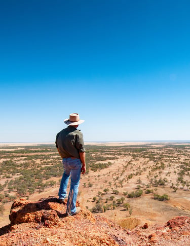 map standing on rock looking over dry landscape, south-western QueenslandAdobeStock