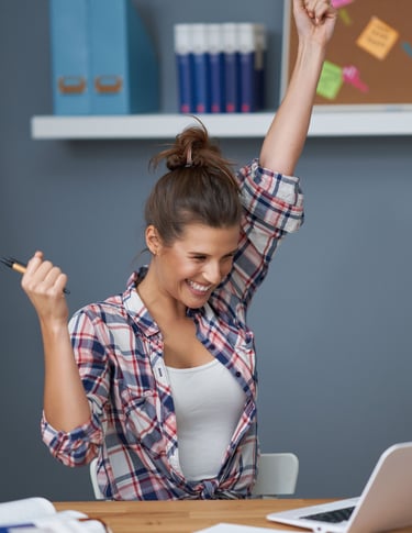 a woman sitting at a desk with her arms up in the air