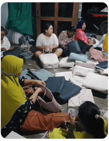 Group of artisans crafting handmade woven plastic bags together at Craftvitas Indonesia production area.