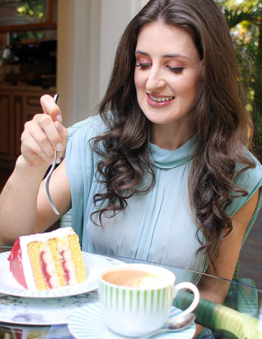 Foto da nutricionista em Jaraguá do Sul, Kamila Kuester, sorrindo enquanto come uma fatia de bolo.