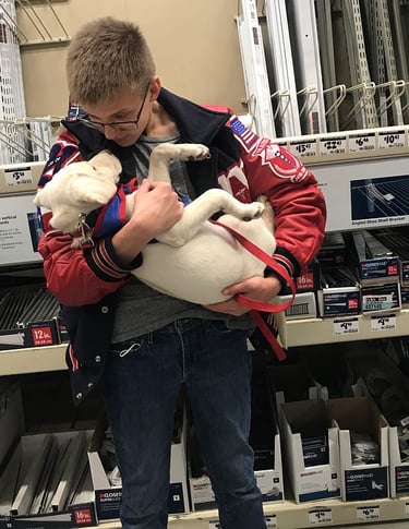 a student puppy raiser cradles his puppy in his arms looking down lovingly at her
