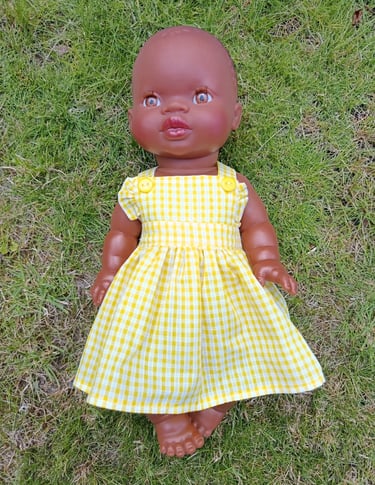 Minikane doll Nia dressed in a yellow gingham dress