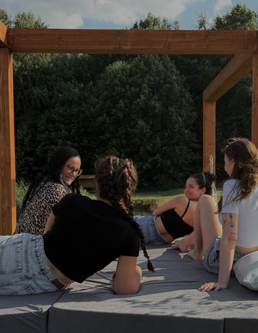 Cztery kobiete uśmiechają się do sibie na konstrukcji pod gołym niebem. Rodzinna atmosfera. 