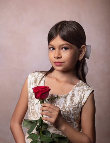 una niña mirando a la camara con una rosa roja en la mano