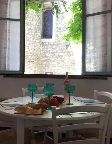 Dining area of holiday home in Quillan with open windows and church view