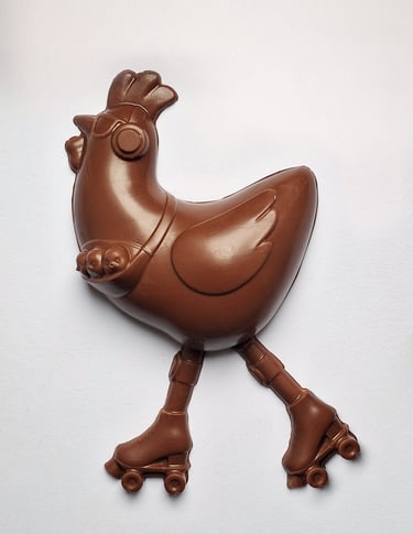 Milk chocolate Easter chicken wearing sunglasses and roller skates on a plain white background.