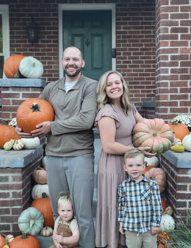 a family posing for a family photo surrounded by pumpkins in front of a house