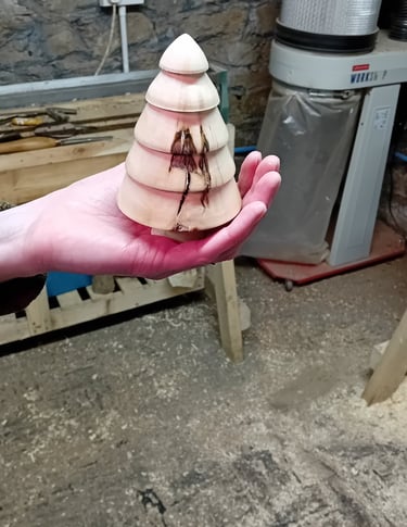 A turned wooden fir tree standing on a hand