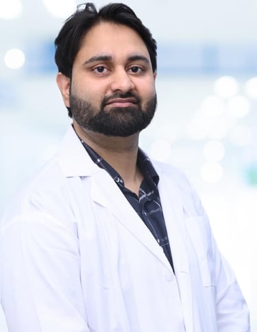 Professional male doctor with a beard wearing a white lab coat in a bright clinic setting.