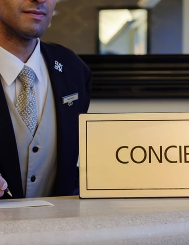 Professional hotel concierge in a formal uniform writing at a luxury service desk with a concierge sign.