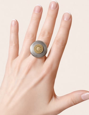 Hand with French manicure wearing a round silver and gold statement ring.