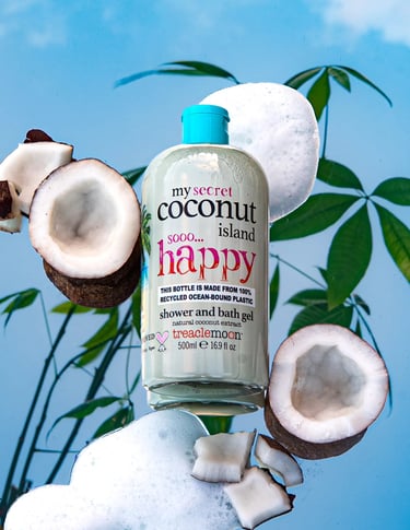 Treaclemoon Coconut Island shower gel styled with coconuts, foam and tropical leaves