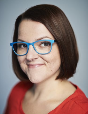 Foto der Geschäftsführerin. Rotes Oberteil und blaue Brille