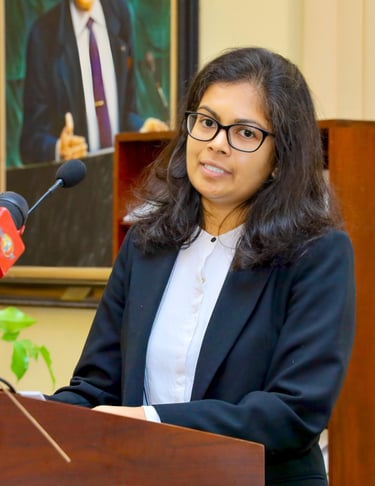 a woman in a suit and glasses speaking into a microphone