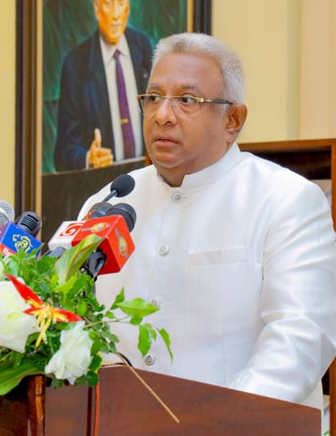 a man in a white suit and glasses speaking into microphones