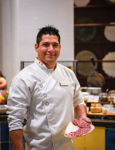 a man in a chef's uniform holding a plate with meat in Marriot Hotel in Herradura Costa Rica