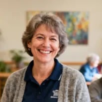 Candid photo of a cheerful activities director in a retirement community, smiling while standing casually with hands relaxed
