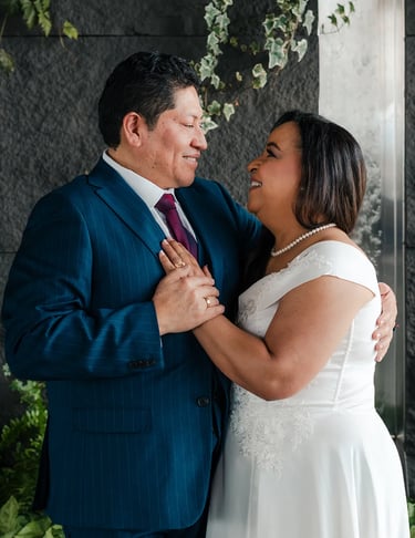 Retrato editorial de novios sonriendo en locación elegante con plantas en Quito. Fotografía documental de bodas premium.