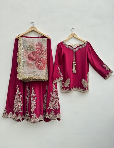 Elegant magenta silk lehenga choli with intricate gold zari embroidery and a floral net dupatta.