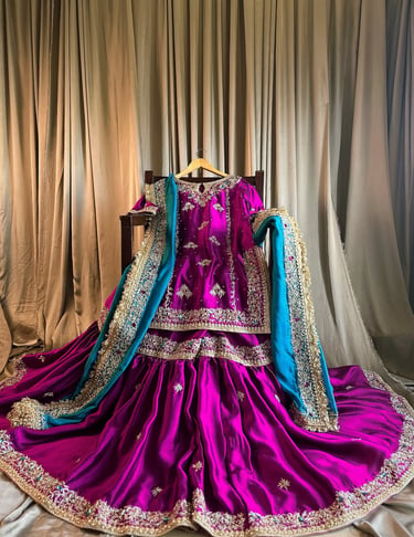 Elegant purple silk sharara suit with gold embroidery and a teal dupatta for traditional bridal wear.