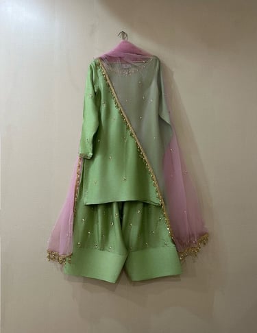 Elegant lime green salwar kameez with embroidered details and a pink net dupatta with gold trim.