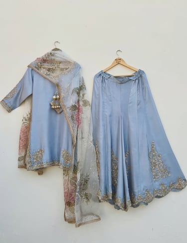 Elegant dusty blue silk lehenga choli with golden embroidery and a floral organza dupatta.