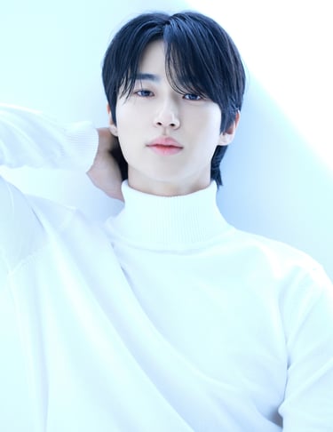 A young man with black hair wearing a white turtleneck sweater in a bright, Byeon Woo-seok