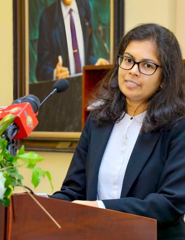 a woman in a suit and glasses speaking into a microphone