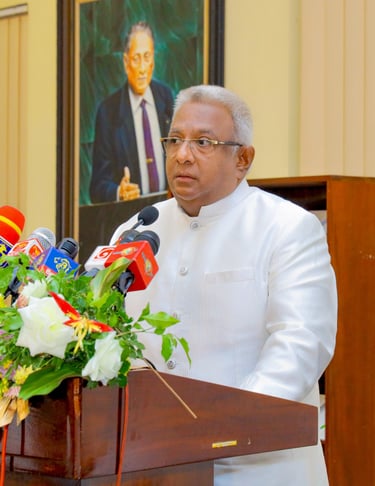 a man in a white suit and glasses speaking into microphones