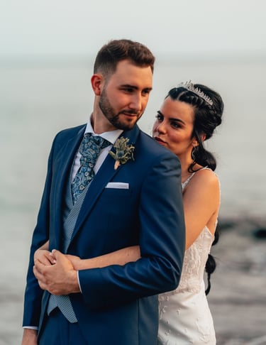 una novia y un novio en una playa abrazándose en el día de su boda