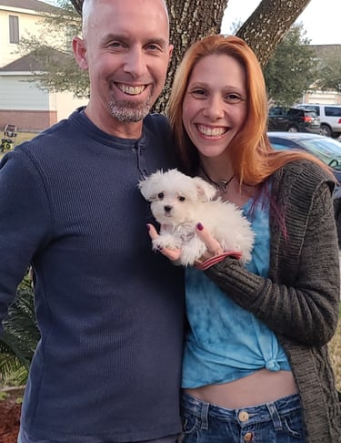 man and woman holding a MalShi puppy