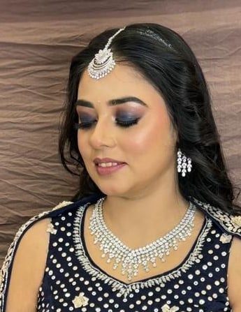 Indian bride-to-be in navy blue lehenga with smokey eye engagement makeup, diamond jewelry, loose cu